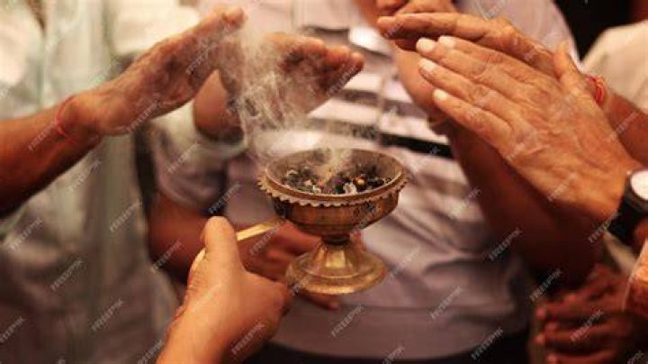 Group of people lights incense as they worship Pol Pot's grave